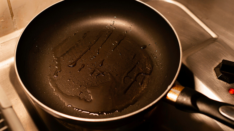 Non-stick frying pan covered in oil on stovetop.