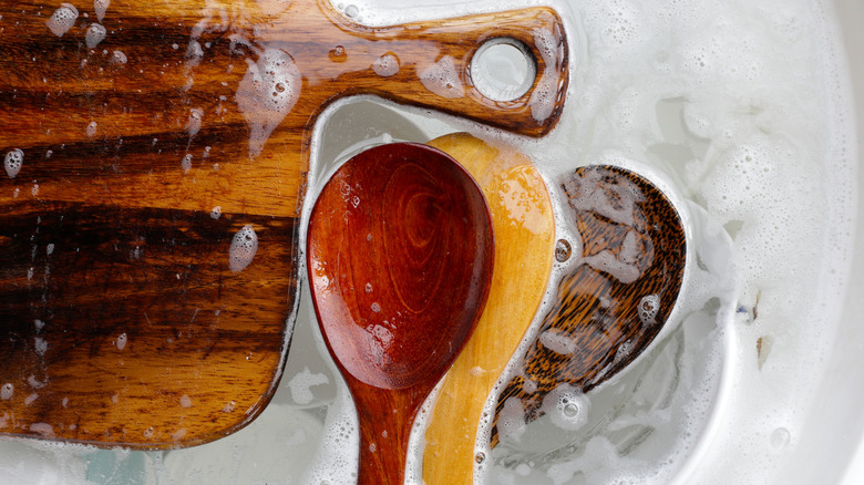 Collection of wooden spoons being washed in soapy water.