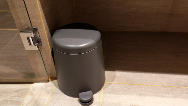 A small gray trash can with a foot pedal in a bathroom