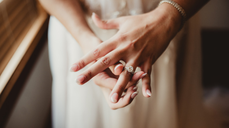A bride adjusting her engagement ring on her wedding day.