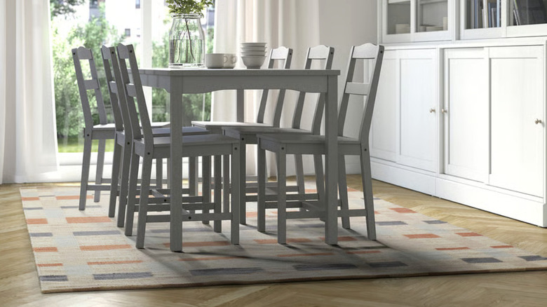 A beige rug with a gray and rust checkered pattern under a gray dining table