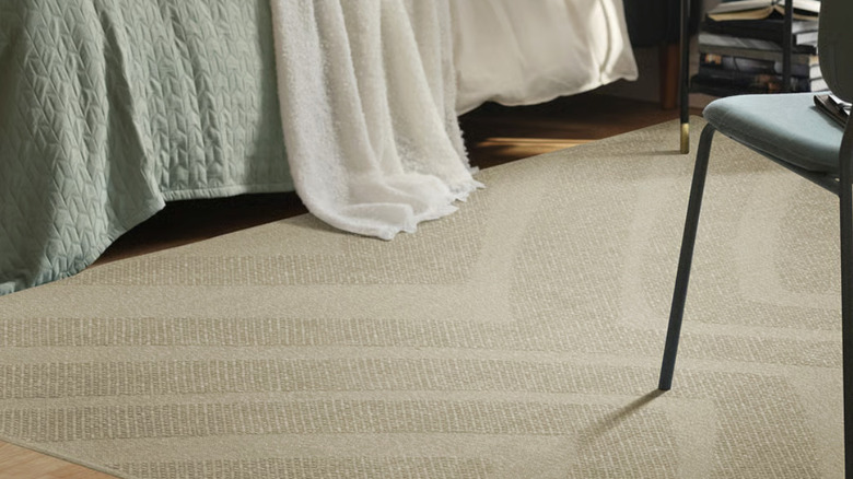 A beige rug with a textured pattern in a bedroom