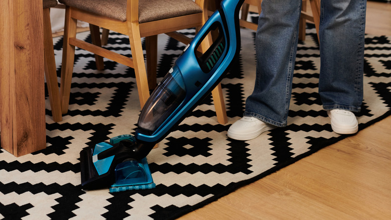 A close-up shot of a woman cleaning a patterned rug in the dining room