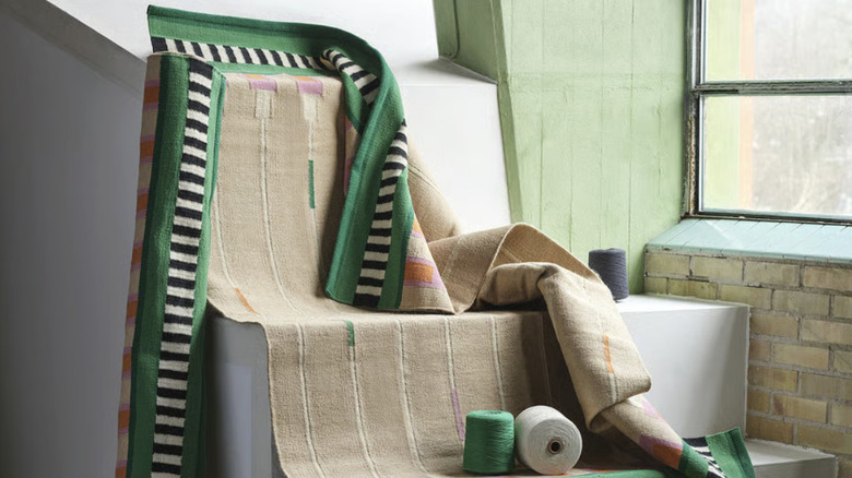 A beige, green, orange, and pink patterned rug draped over stairs