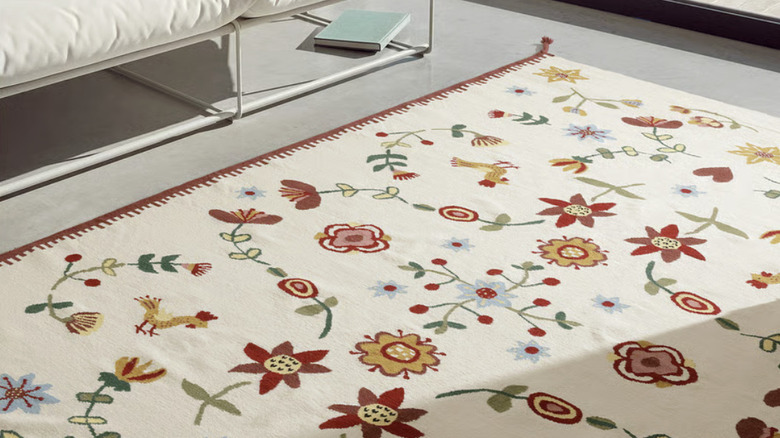 A rug with red, green, and yellow folky florals on a beige background