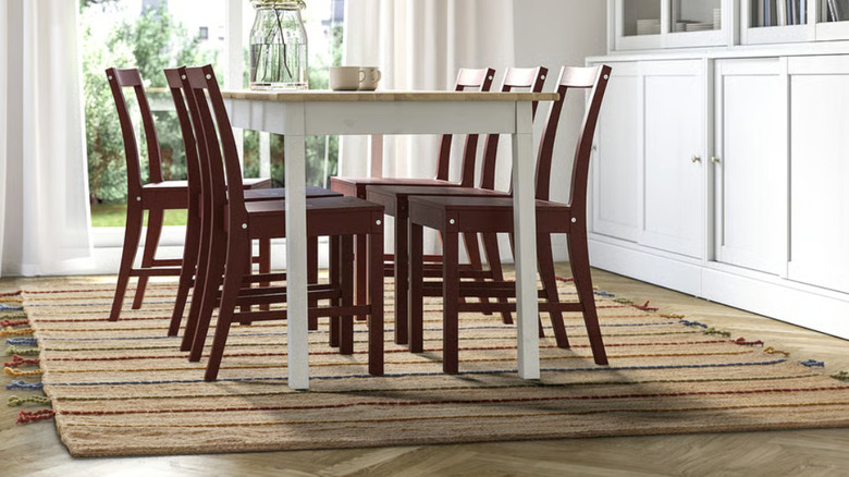 A beige rug with multicolored stripes styled in a living room under a red dining set