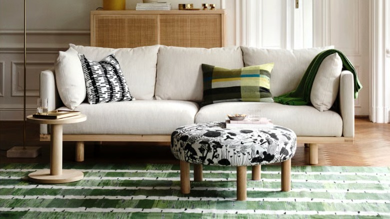 A green organic pattern rug styled in a neutral, modern living room