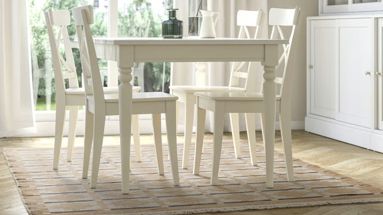 A yellow and beige flatwoven rug under a dining set