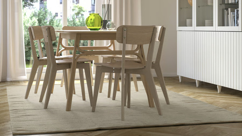A beige flatwoven rug under a light wood dining set
