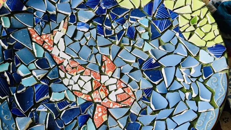 A mosaic birdbath with a clear image of a koi fish made from broken china.