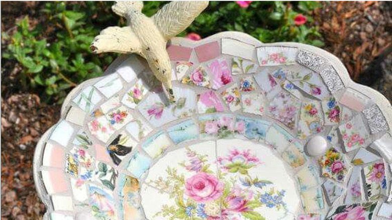 A mosaic bird bath made from broken vintage china in a flower pattern.