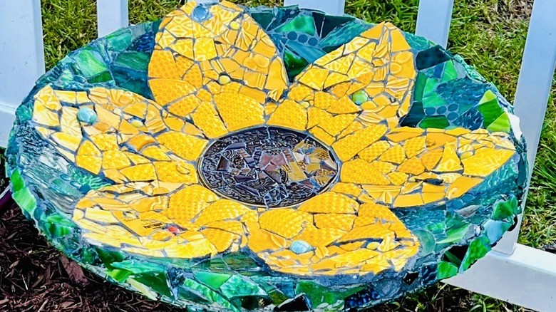 Mosaic bird bath depicting a sunflower with both flower and background in deep colors.