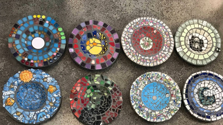 Eight mosaic bird baths, most made primarily from broken china dishes.