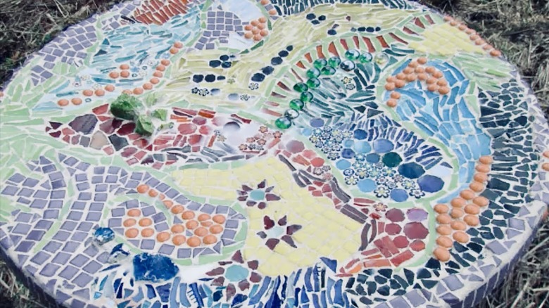 A mosaic birdbath made from an old satellite dish and containing an intricate pattern of broken china.