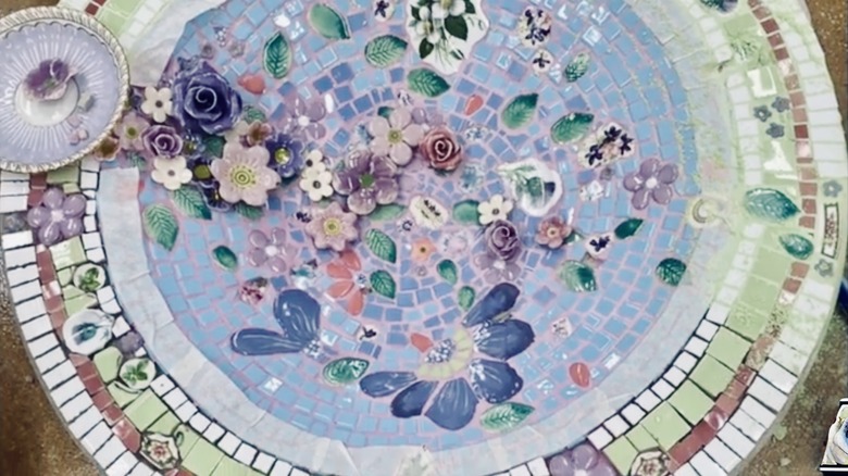 A mosaic bird bath with both tiles and broken china, along with 3D pieces.