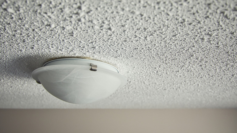 A popcorn ceiling with a glass light fixture.