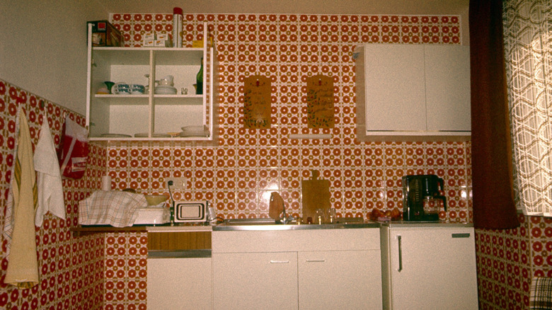 A 1970s kitchen with red patterned tile on all the walls.