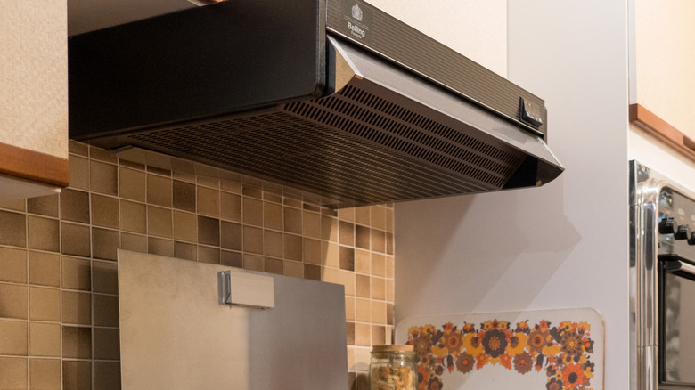 A dark brown metal range hood in a 1970s kitchen.