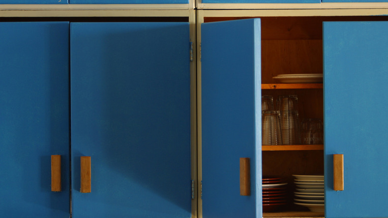 1970s wooden cabinet handles on blue kitchen cabinet doors.