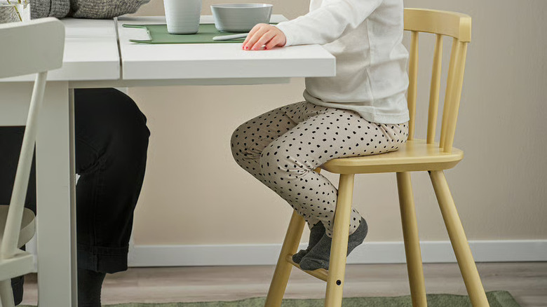 Young girl sitting on the AGAM junior chair at a table