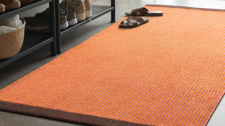 The VÄGOMRÅDE Rug on the floor with a shoe rack in the background