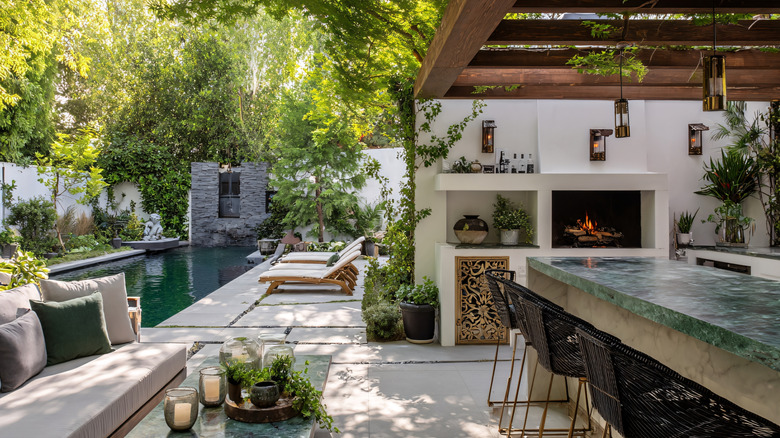 Beautiful Mediterranean style patio featuring an outdoor kitchen and a lush backyard garden in background