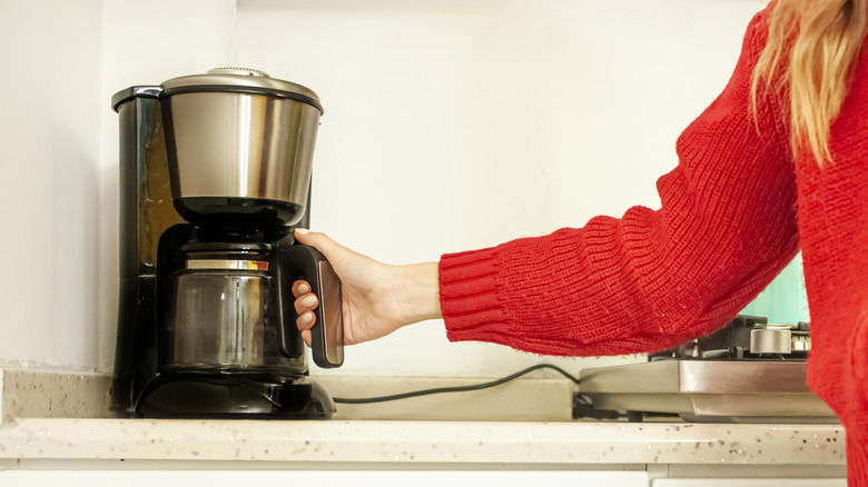 An person using an old electric coffee maker