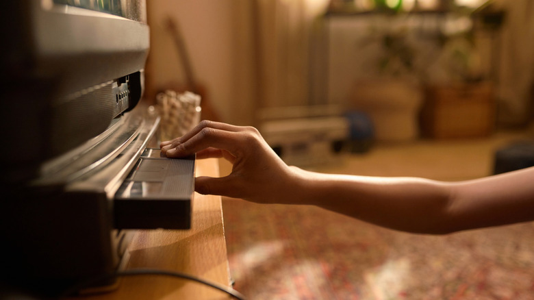 A hand inserting an old tape into a video cassette player