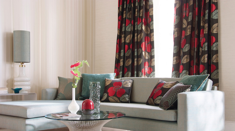 Dark leaf-print drapes that match a sofa's throw pillows