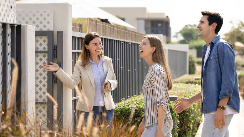 realtor showing happy people a modern looking house