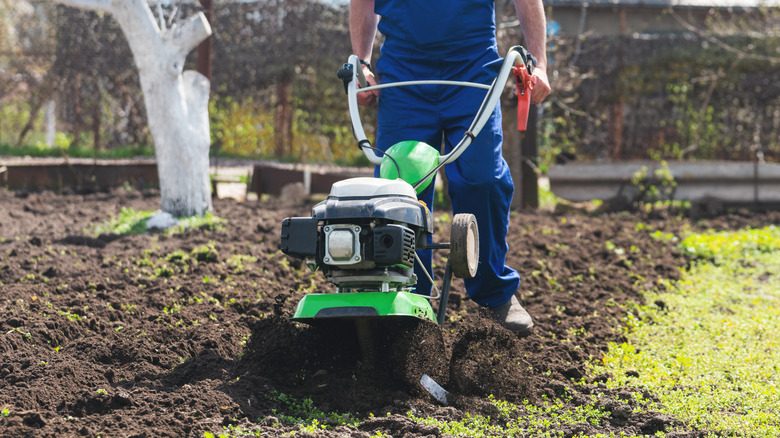 Man working garden soil with a garden cultivator
