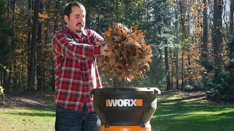 Man putting fall leaves into a Worx leaf mulcher