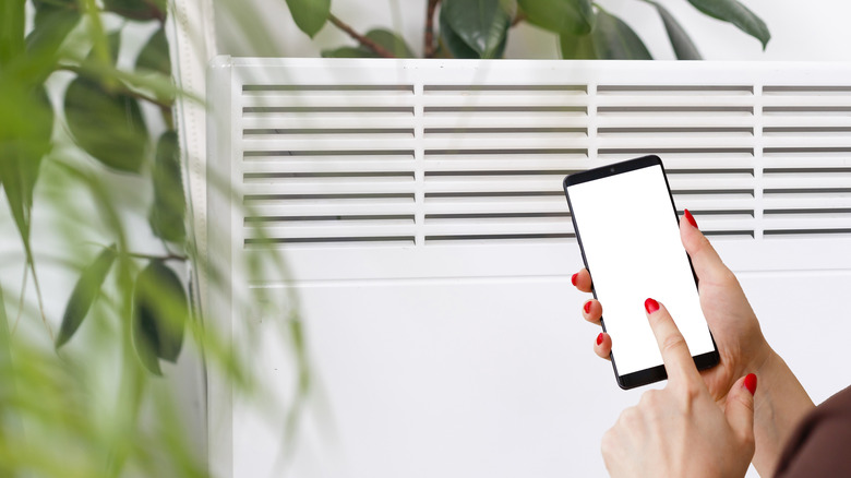 A person controlling their electric heating via their smartphone