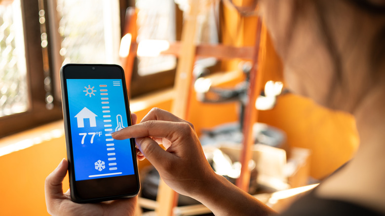 A woman controlling her home's heating from her smartphone