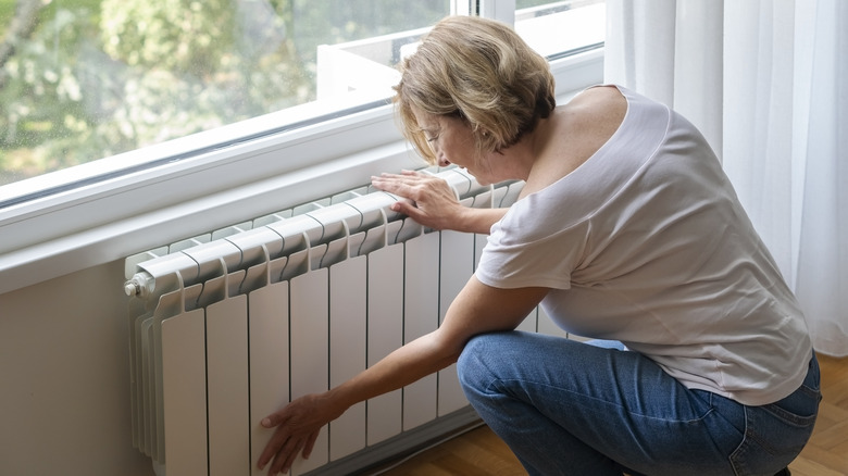 A woman using a wall-mounted electric radiator