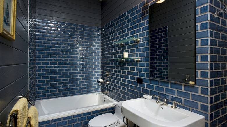 Small bathroom covered in small dark blue tiles