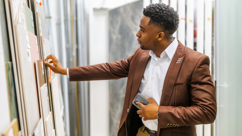 Man wearing a jacket while looking at different tiles and materials in a showroom