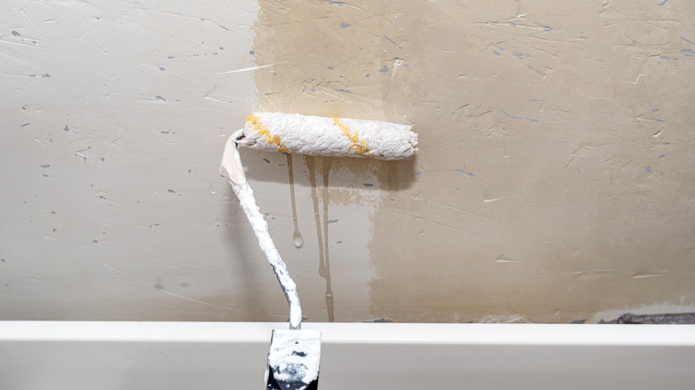 A roller applying primer to a wall