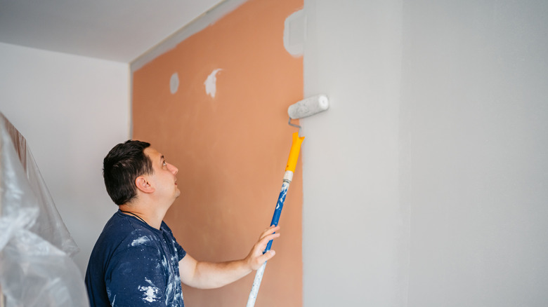 A man painting over old paint with new paint
