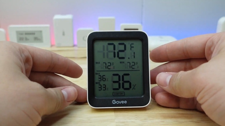 Hands closing around a small temperature and humidity sensor