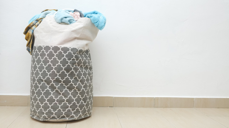 A hamper filled with laundry, including towels