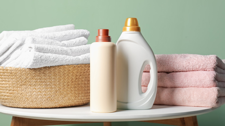 A laundry basket with towels and bottles of detergent
