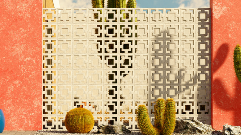 A breeze block wall in front of a desert home.