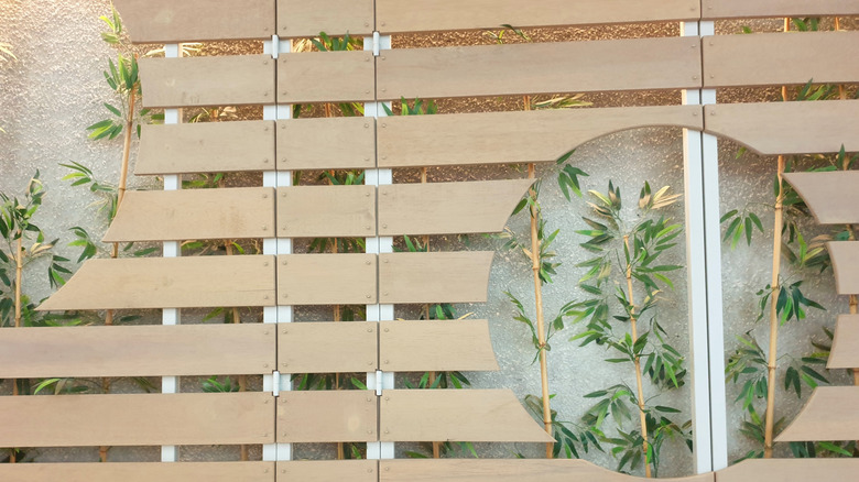 A wooden screen with bamboo behind.