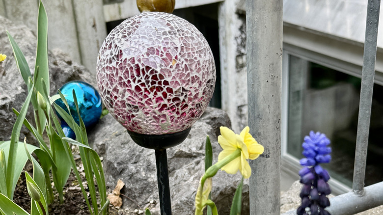 A purple glass gazing ball in a garden.