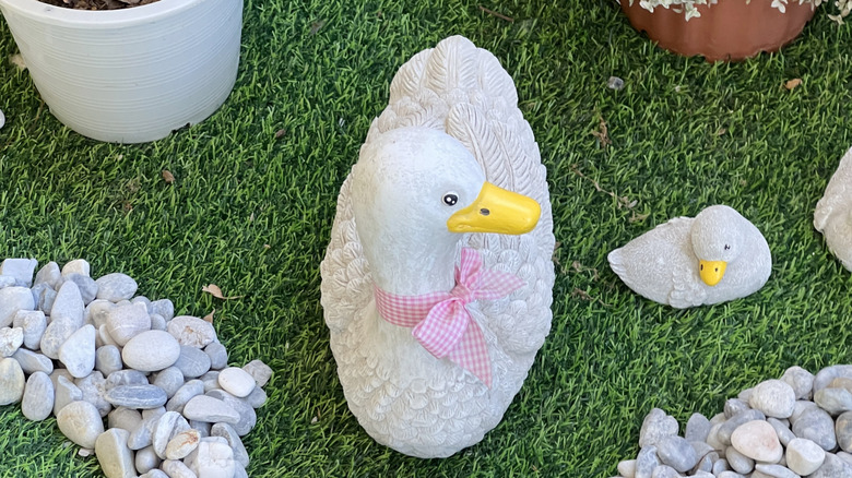 Two garden geese on fake grass.