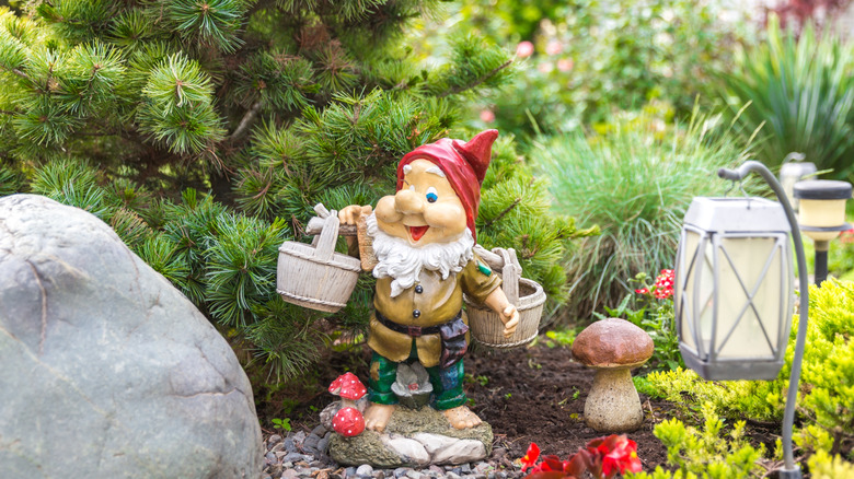 A smiling garden gnome statue in a yard.
