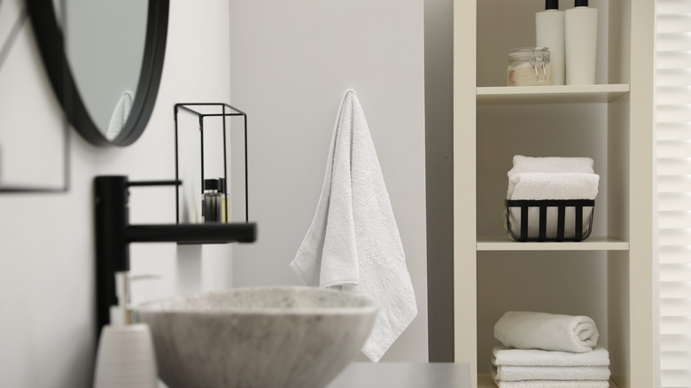 A bathroom sink with storage cupboards behind it.
