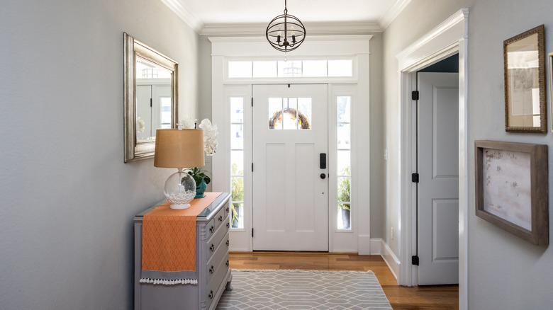A large hallway with white walls and door with a gray sideboard with multiple drawers.