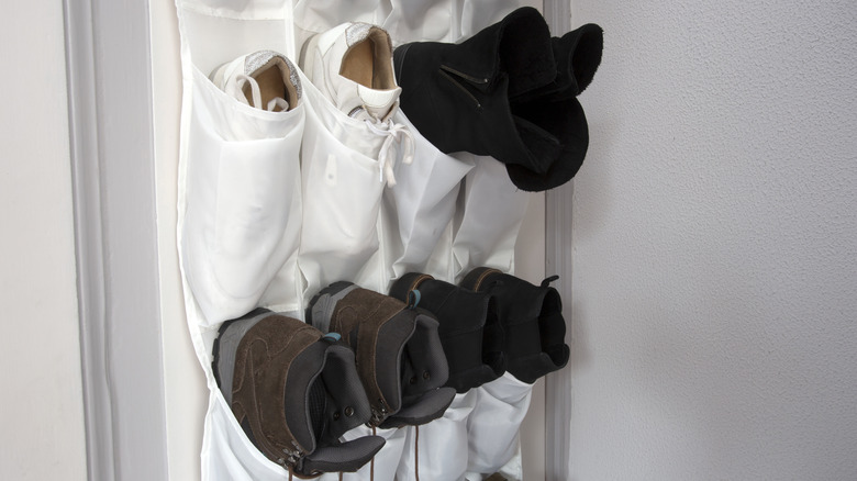 A shoe storage door organizer with trainers and boots in it.